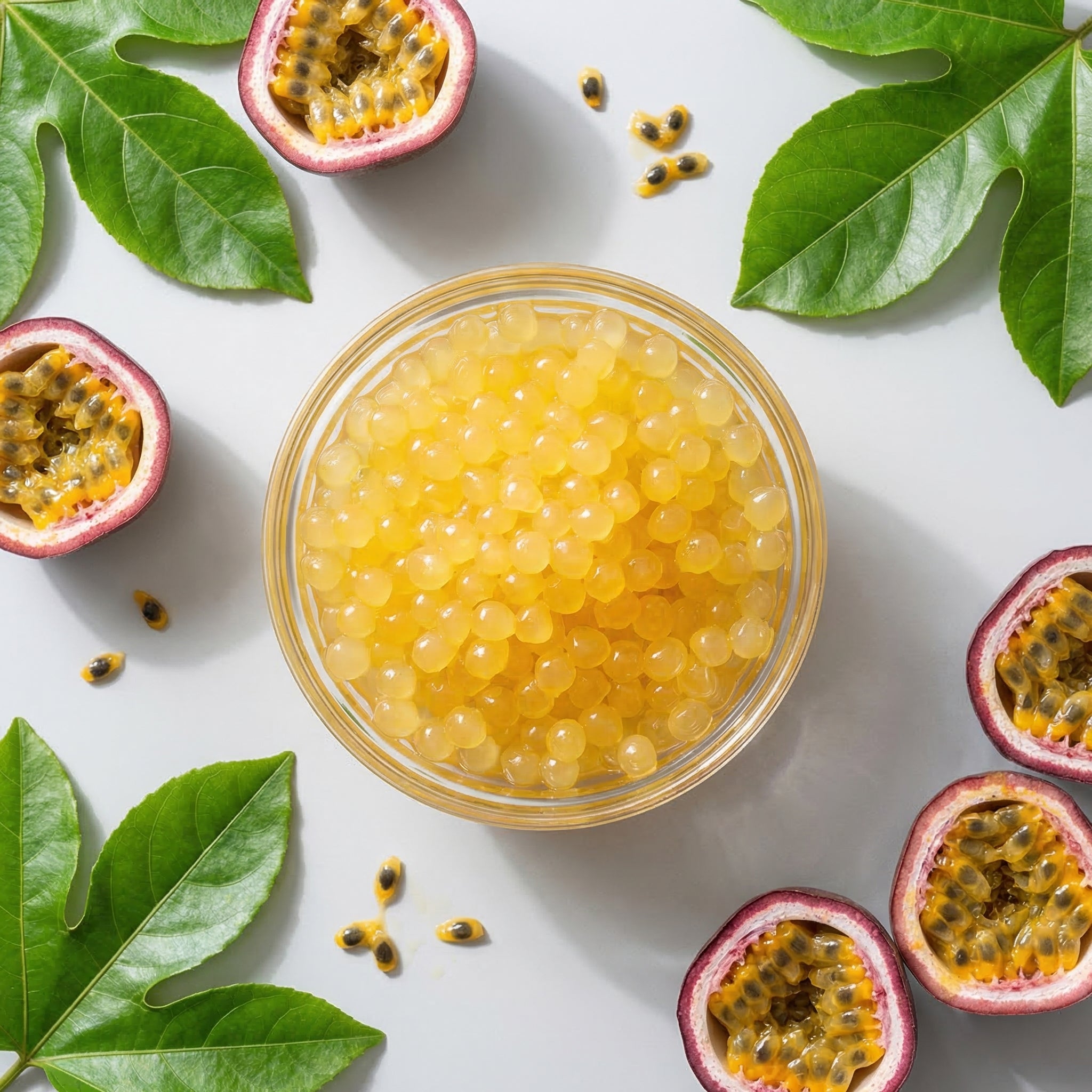 Passion fruit bursting boba in a glass bowl with passion fruits and leaves on a white background
